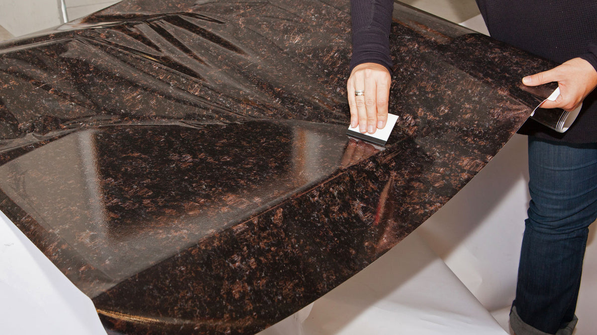 Using a squeegee to help smooth out Chestnut Instant Granite Faux Countertop vinyl.